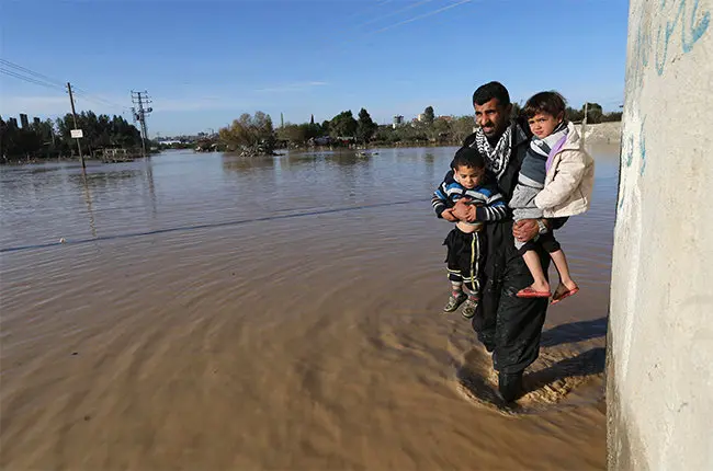 Un palestino lleva en brazos a dos ni&ntilde;os durante la evacuaci&oacute;n en el poblado de Al-Moghraga (Reuters - Ibraheem Abu Mustafa)