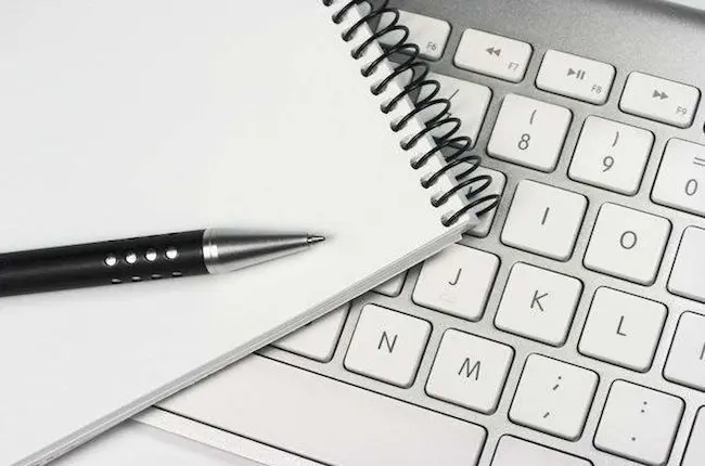 Teclado de ordenador, blog de notas y bolígrafo.