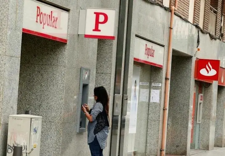 Una mujer retira dinero de un cajero del Banco Popular. / Twitter