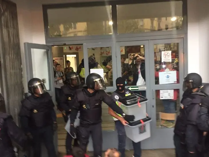 Un policía nacional requisa unas urnas. / Twitter