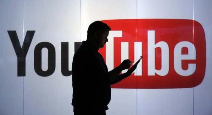 Un hombre con un dispositivo y de fondo se observa el logo de YouTube. / RRSS.