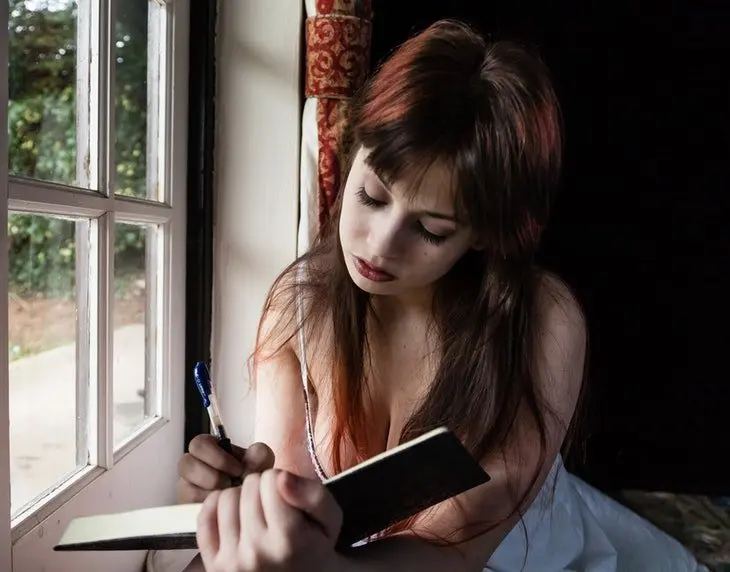 Mujer sexy escribiendo en un cuaderno. / Pexels.com.