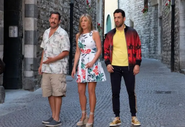 Adam Sandler, Jennifer Anistor y Luis Gerardo Mendez en la pel&iacute;cula Murder Mystery. / Collider.