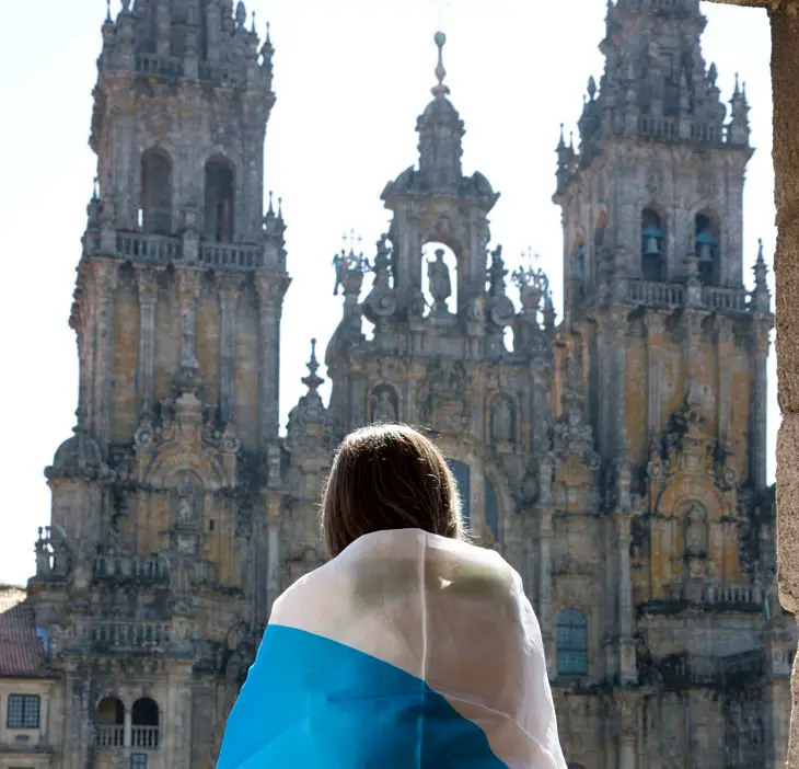 Una joven con la bandera de Galicia ante la Catedral de Santiago. / Xurxo Lobato