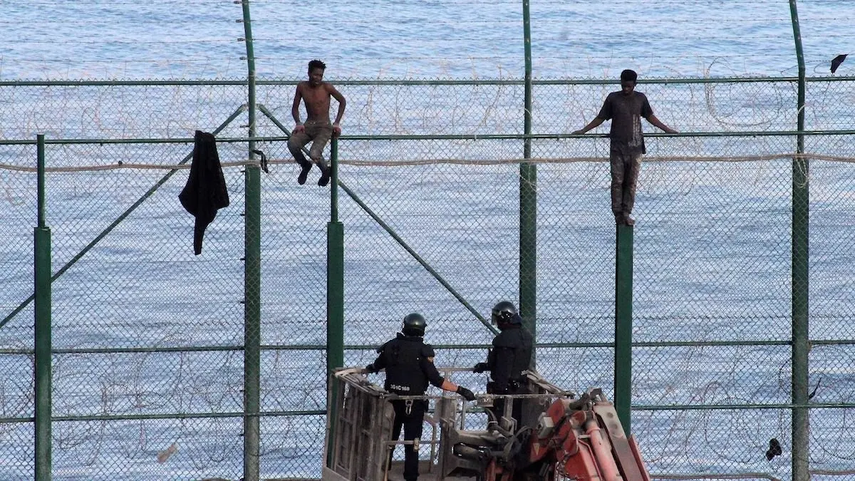 Inmigrantes subidos a la valla de Ceuta. /  Mundiario