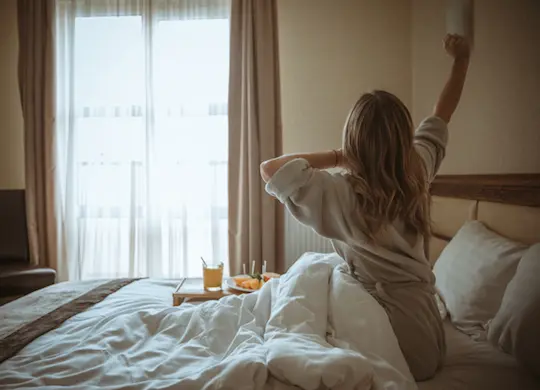 Mujer despertando en un hotel.