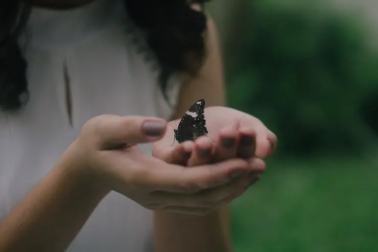 Mariposa posada en unas manos. / Reign Abarintos. / Unsplash