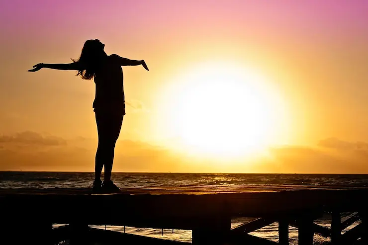 Una mujer disfruta de una puesta de sol. / Pixabay