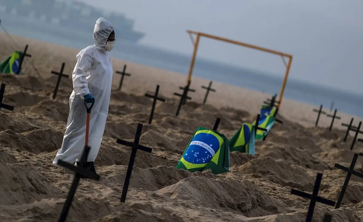 Un trabajador de un cementerio protegido con un traje de bioseguridad entierra a personas fallecidas por covid-19 en Sao Paulo, Brasil. / Diario O Globo