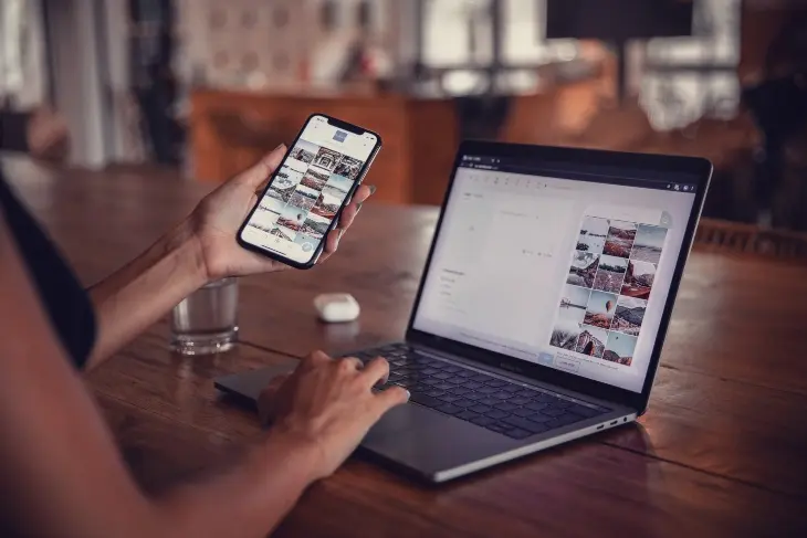 Una mujer sosteniendo un m&oacute;vil junto a una laptop. / Pexels.