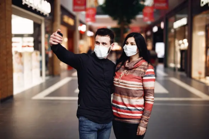Dos personas con mascarilla se hacen un selfie. Freepik.