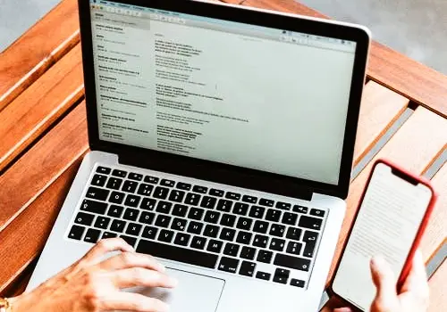 Una persona con un portatil y un m&oacute;vil. Pexels.