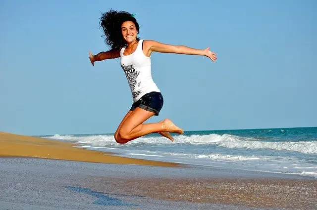 Mujer saltando de felicidad al aire libre./ Messan Edoh en Pixabay