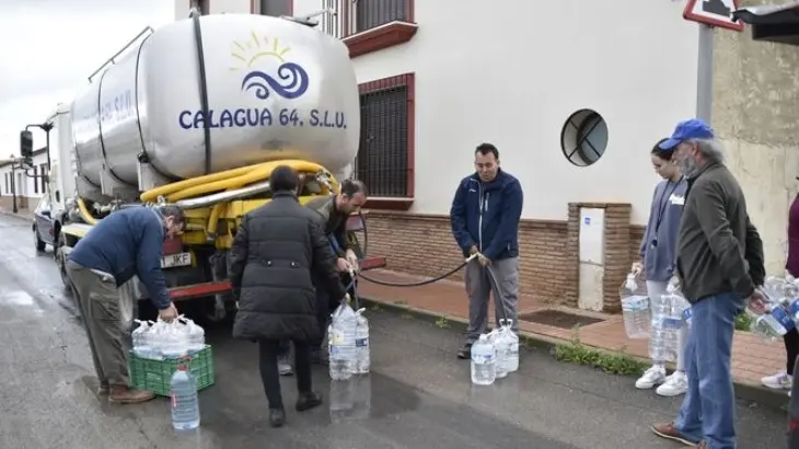 Varios vecinos de Humilladero (M&aacute;laga) rellenan garrafas de agua de un cami&oacute;n cisterna, al no poder beber agua del grifo. / RR SS.