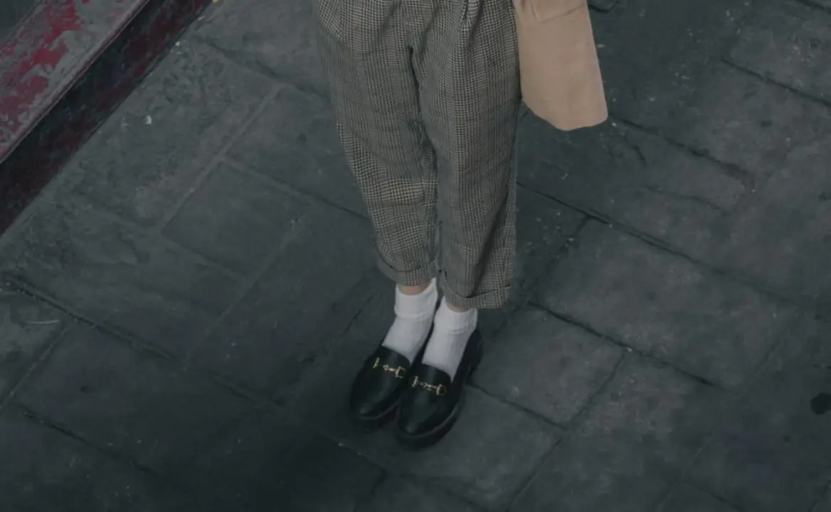 Mujer usando mocasines negros estilo Prada.