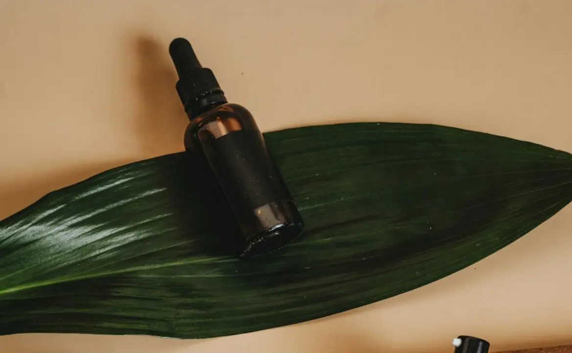 Envase de serum facial con aplicador de gotero sobre una hoja natutal.