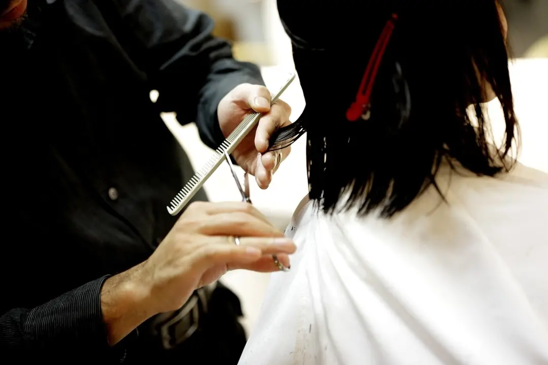 Un estilista cortando el cabello de una mujer. / Pixabay.