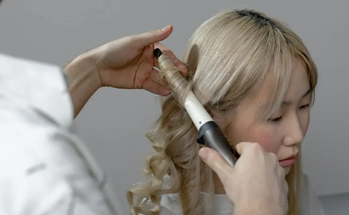Mujer con tenaza de pelo y rizos.
