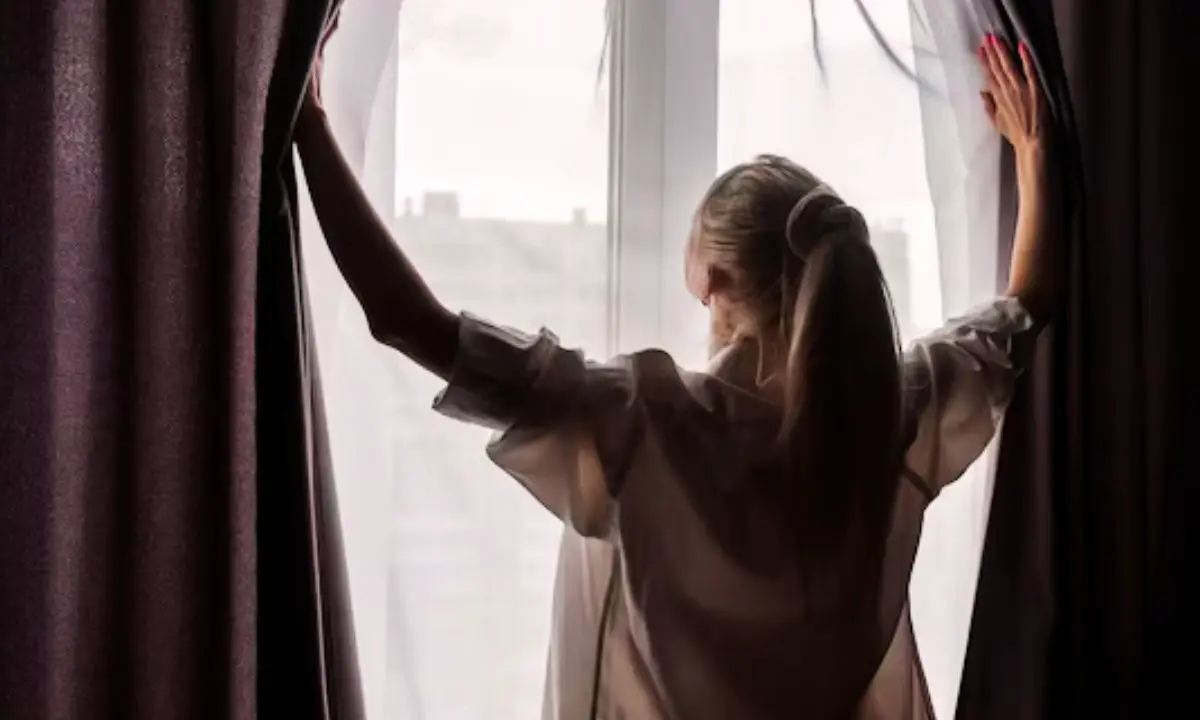 Una mujer se asoma en una ventana. / Freepik.