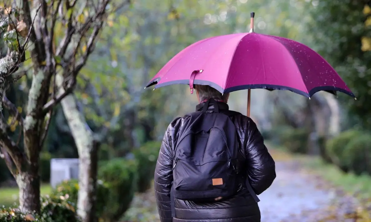 Una mujer lleva un paraguas para curbrirse de la lluvia. / @Xunta.