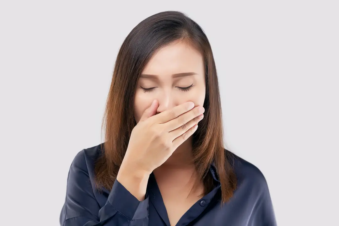 Portrait of tired girl who yawns. A woman yawning on a light gray background
