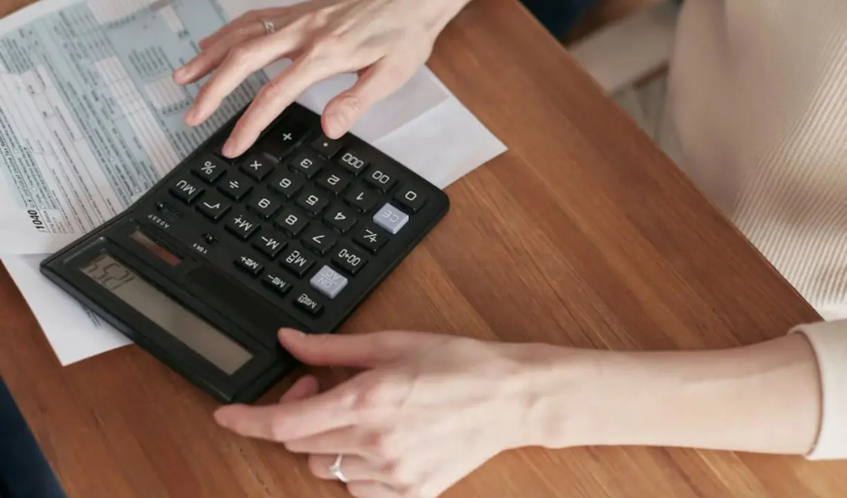 Una mujer usando una calculadora. / Pexels.