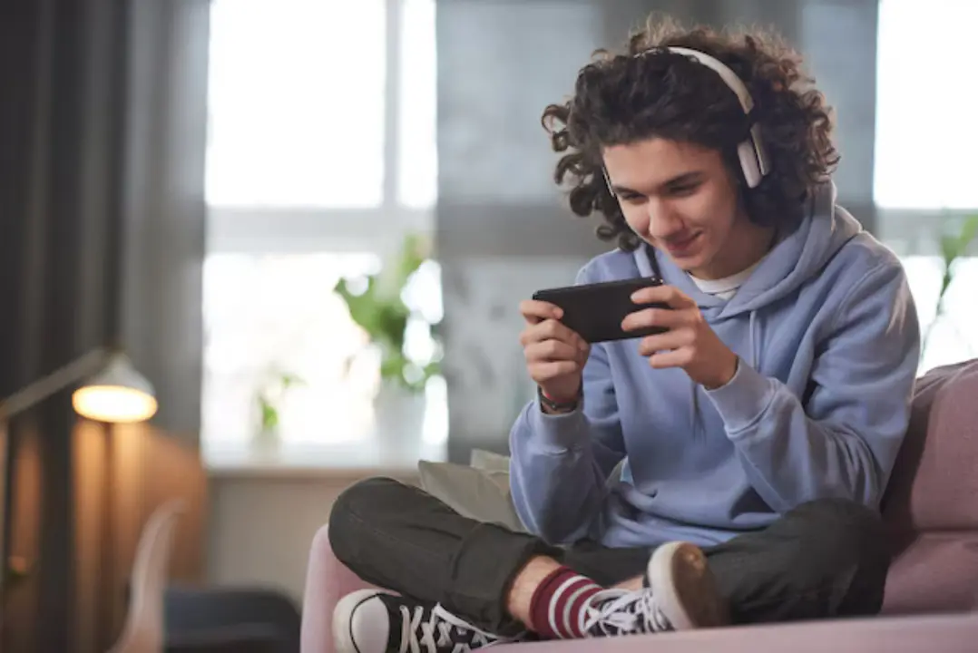 Un adolescente con su m&oacute;vil y auriculares. / Freepik.