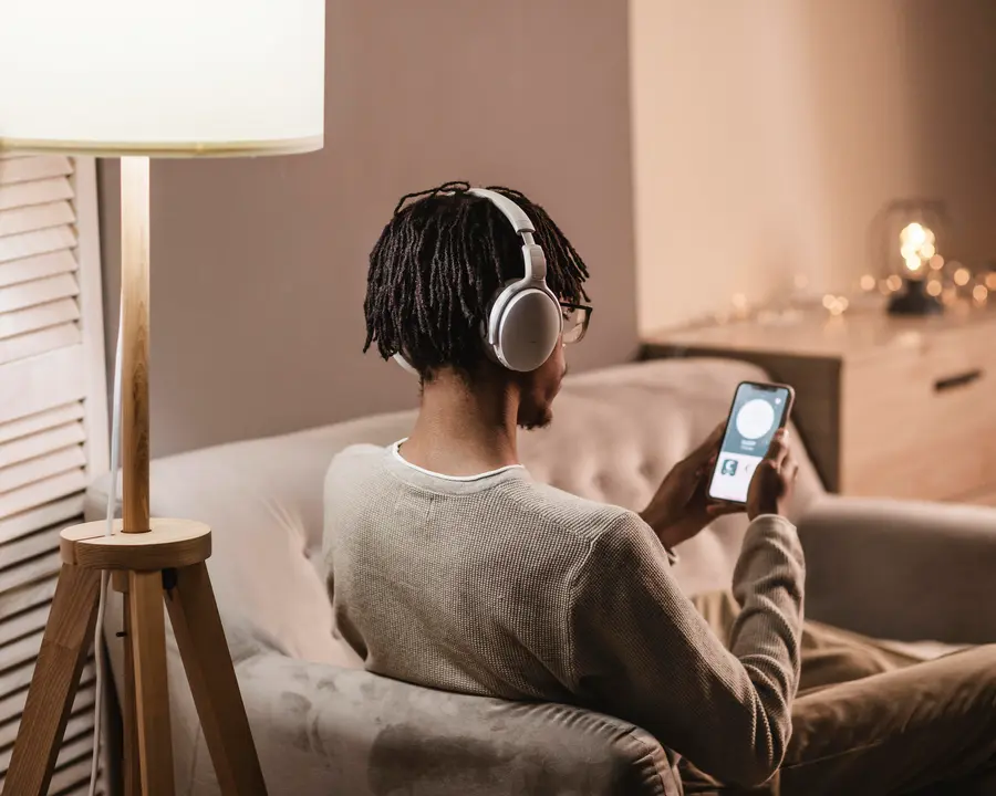 hombre-en-casa-en-el-sofa-con-smartphone-y-auriculares