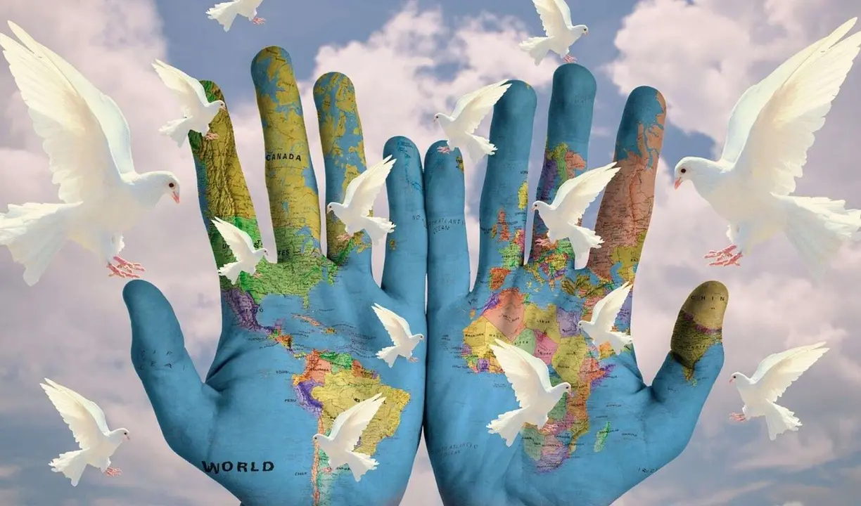 Unas manos con el mapa del mundo y palomas de la paz. / RR SS.
