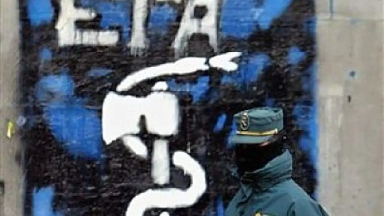Un guardia civil con una pintada del s&iacute;mbolo de ETA al fondo.
