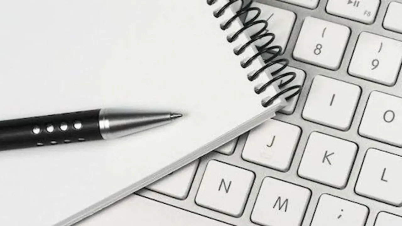 Teclado de ordenador, blog de notas y bolígrafo.