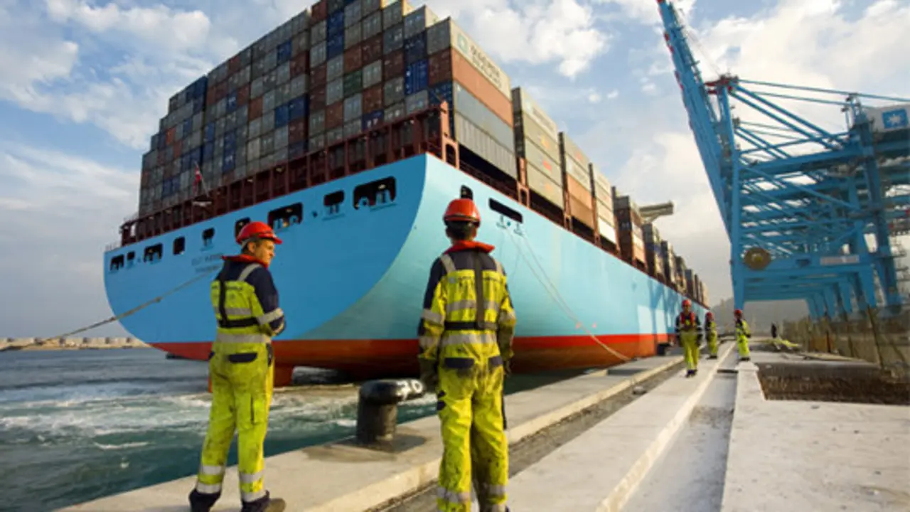 Estibadores ante un barco portacontenedores. / Mundiario