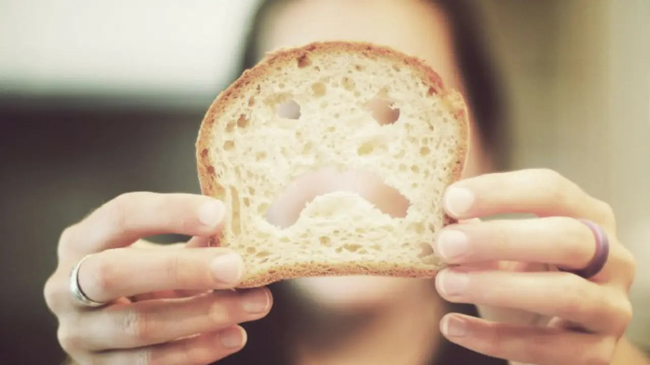 Mujer mostrando una rebanada de pan, alimento con gluten. / RRSS.