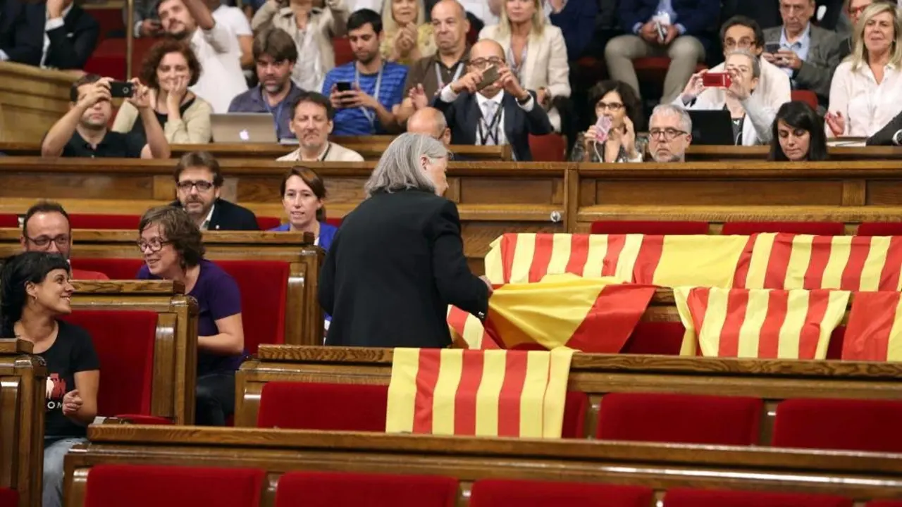 Una diputada de Podemos retira una bandera espa&ntilde;ola de la bancada del PP &ndash;vac&iacute;a&ndash; en el Parlamentio de Catalu&ntilde;a. / Twitter