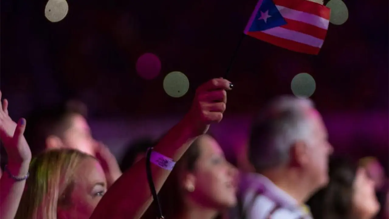Una asistente al concierto levanta una bandera de Puerto Rico./ RRSS
