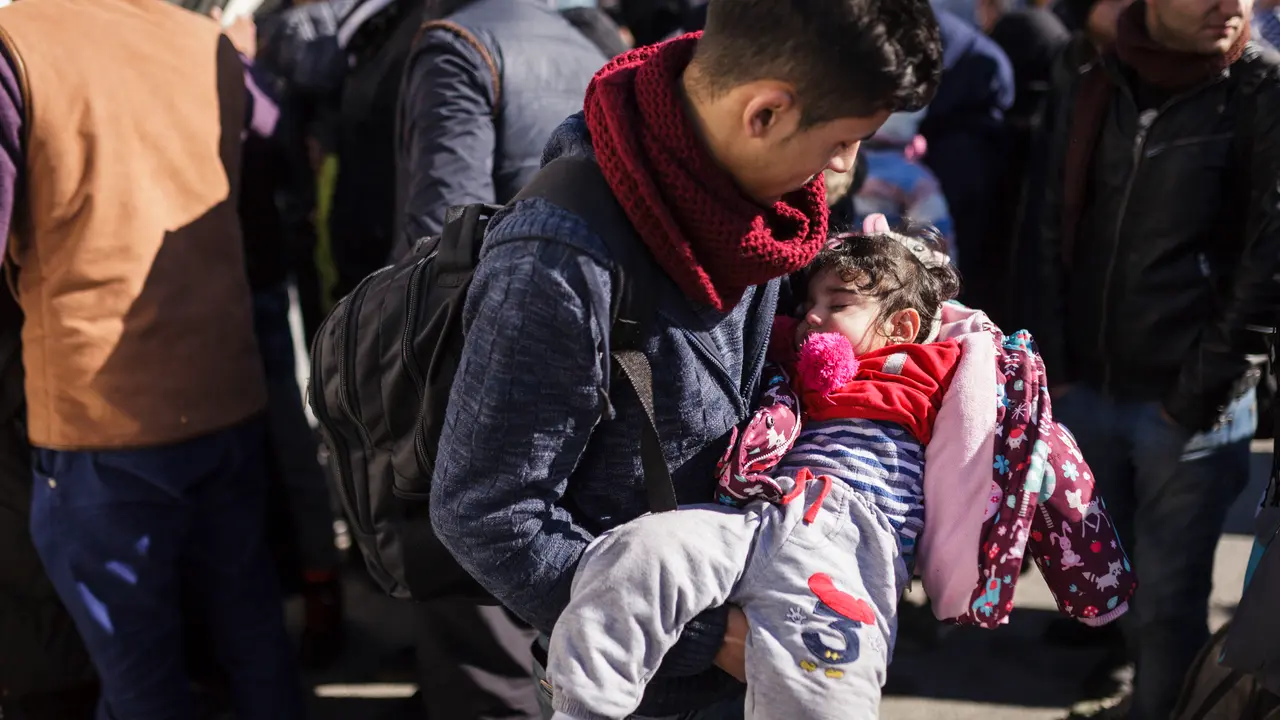 A young man from Syria holds his young daughter in the port of Mytilene while waiting to board a UNHCR bus that will transport them to the Moria Reception / Registration center. ; More than 900.000 refugees and migrants arrived in Greece since January 2015. 
Despite rough seas and freezing water temperatures they continue crossing the Aegean sea from Turkey to the Greek islands in overcrowded inflatable boats, many arriving to the Greek shores in a state of shock and suffering from hypothermia.
Vulnerable groups like women, children and the elderly are amongst the ones who are often in danger during the perilous boat ride that can take hours. 
In an effort to save lives and assist those in need the Hellenic Coast Guard in cooperation with Frontex have increased their search and rescue operations in the Aegean, often rescuing hundreds of refugees and migrants on a daily basis.
The vast majority of those attempting the treacherous journey are fleeing war, persecution and violence in their country of origin and are in need of international protection.