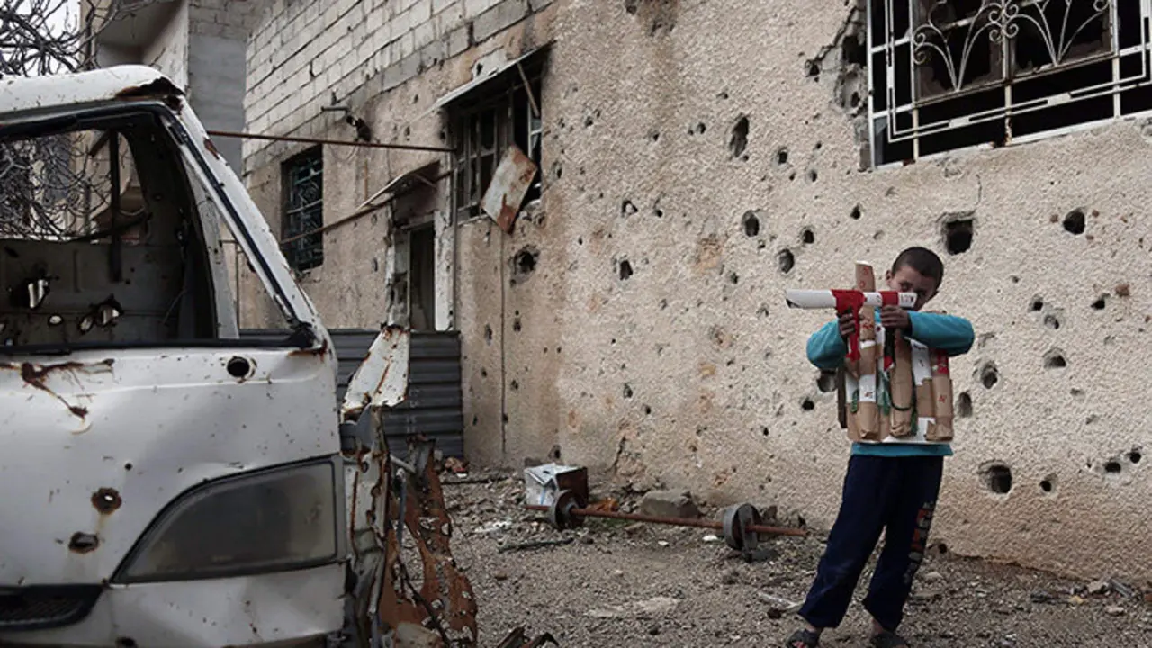 A Syrian child plays with a cardboard gun in the rebel-held town of Harasta, in the Eastern Ghouta region on the outskirts of Damascus on January 25, 2018. / AFP PHOTO / ABDULMONAM EASSA SYRIA-CONFLICT