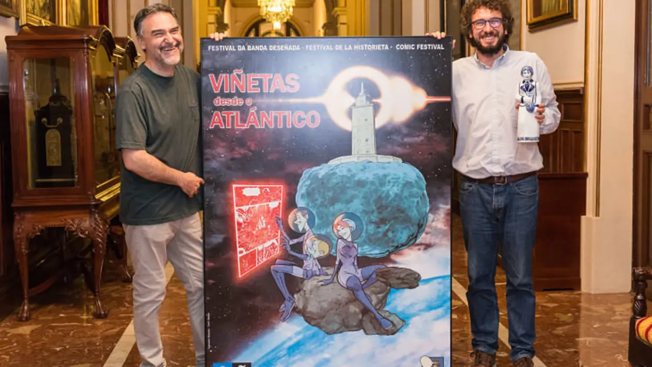 Miguelanxo Prado, director de Vi&ntilde;etas desde o Atl&aacute;ntico, junto Jos&eacute; Manuel Sande, exconcejal de Cultura del Concello da Coru&ntilde;a, con el cartel de la XXI edici&oacute;n, dise&ntilde;ado por Munuera. / Concello de A Coru&ntilde;a