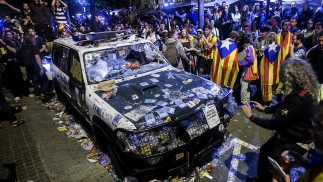 Un veh&iacute;culo de la Guardia Civil destrozado por manifestantes en Barcelona. / RR SS