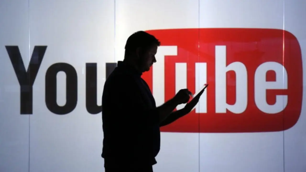 Un hombre con un dispositivo y de fondo se observa el logo de YouTube. / RRSS.