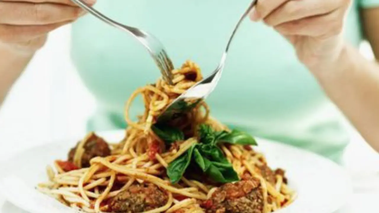 Una persona comiendo pasta con tenedor y cuchara. / The Globe and Mail.