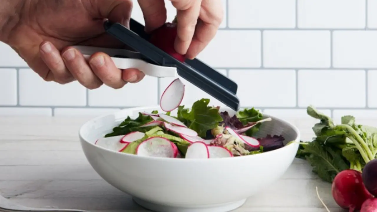 Una persona usando una mandolina. / Epicurious.