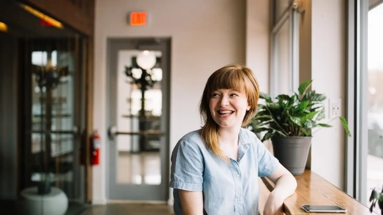 Mujer sentada y sonriendo. / Brooke Cagle. / Unsplash