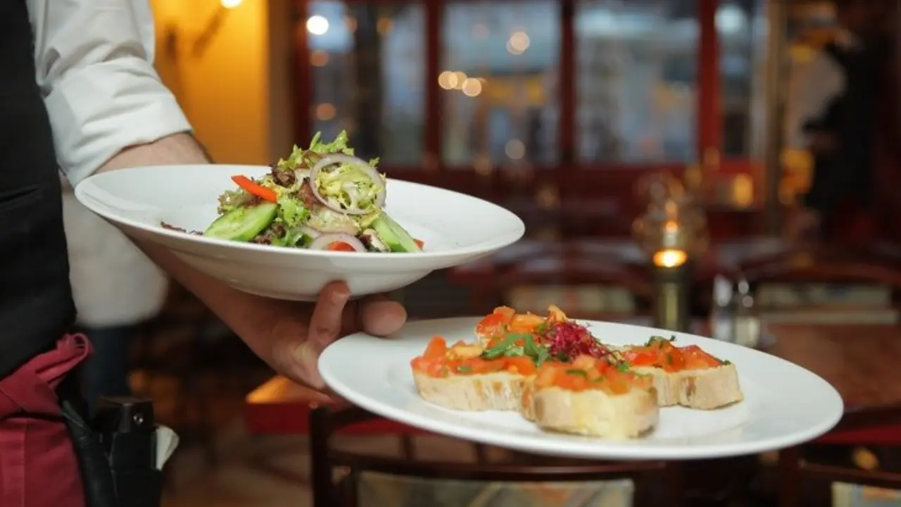 Un camarero sosteniendo platos de comida. / Pexels.com.