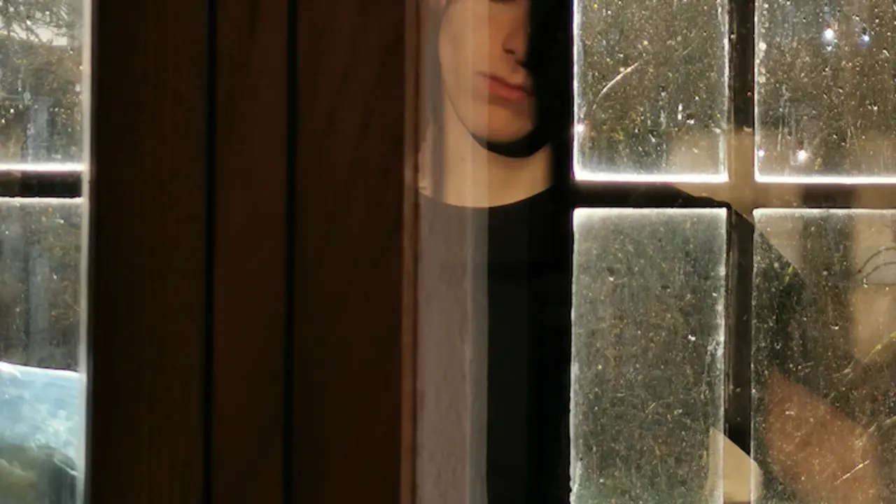 Hombre tras una ventana. / Finn Heraghty. / Unplash