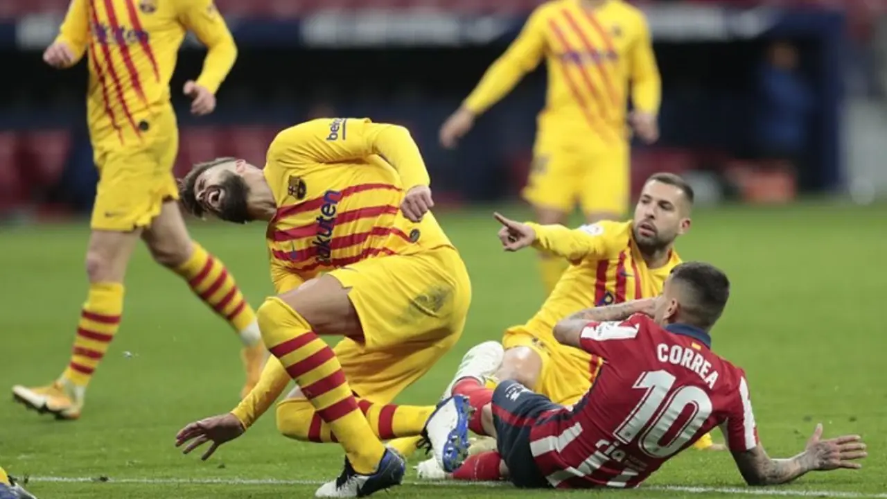 Barcelona's Gerard Pique, left, reacts after getting an injury in a challenge with Atletico Madrid's Angel Correa during the Spanish La Liga soccer match between Atletico Madrid and FC Barcelona at the Wanda Metropolitano stadium in Madrid, Spain, Saturday, Nov. 21, 2020. (AP Photo/Bernat Armangue)