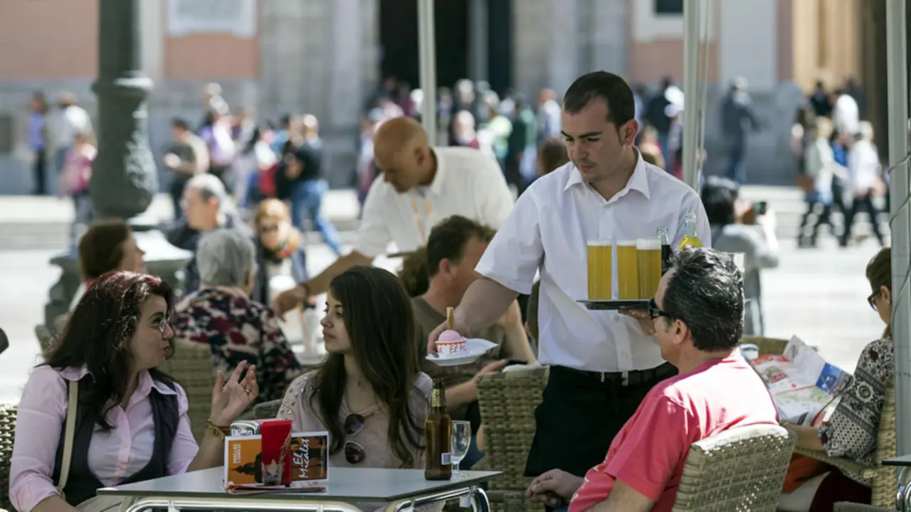 Un camarero sirve bebidas en una terraza en la plaza de la Virgen de Valencia. / Manuel Bruque