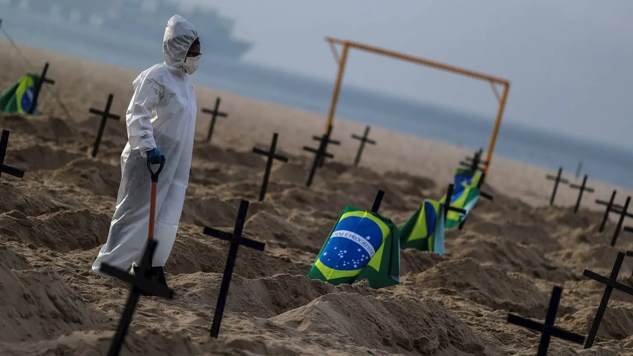 Un trabajador de un cementerio protegido con un traje de bioseguridad entierra a personas fallecidas por covid-19 en Sao Paulo, Brasil. / Diario O Globo