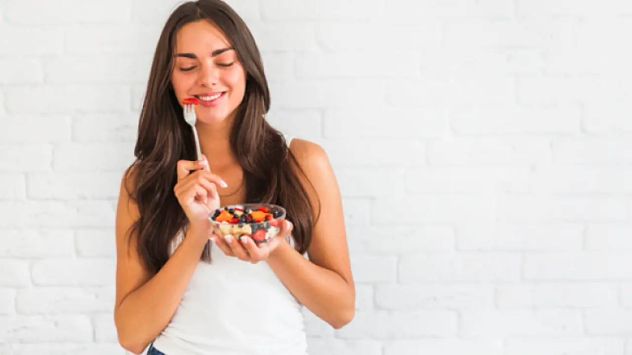 Una mujer con un plato de frutas y yogurt. / Freepik.