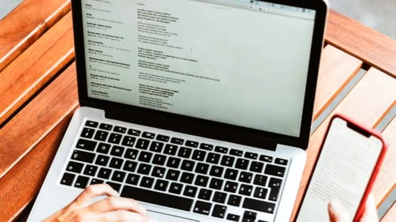 Una persona con un portatil y un m&oacute;vil. Pexels.